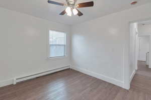 Spare room with ceiling fan, light hardwood / wood-style flooring, and a baseboard heating unit