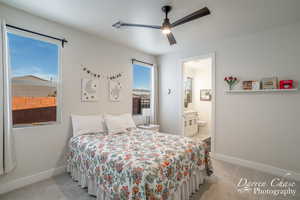 Carpeted bedroom featuring ensuite bathroom and ceiling fan