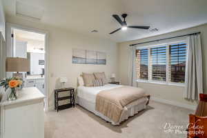 Carpeted bedroom with connected bathroom and ceiling fan