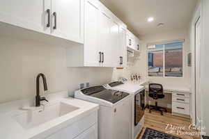 Laundry room with washer and dryer, cabinets, light wood-type flooring, and sink