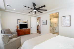 Carpeted bedroom with ensuite bath and ceiling fan