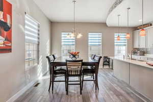 Dining space with light hardwood / wood-style flooring and an inviting chandelier