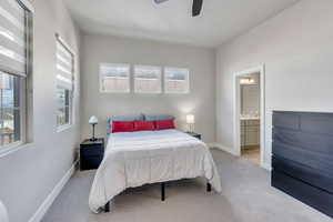 Bedroom featuring light carpet, ensuite bath, multiple windows, and ceiling fan