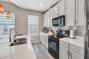 Kitchen featuring black appliances, plenty of natural light, pendant lighting, and sink