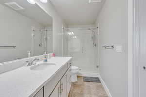 Bathroom with tile patterned floors, vanity, toilet, and a shower with shower door