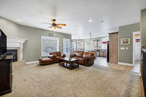 Living room with a tiled fireplace, ceiling fan, sink, and light tile patterned floors