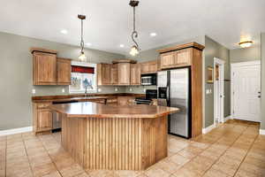 Kitchen featuring sink, a kitchen island, hanging light fixtures, and appliances with stainless steel finishes