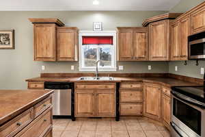 Kitchen with light tile patterned floors, sink, and appliances with stainless steel finishes