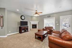 Carpeted living room with ceiling fan, a textured ceiling, and a tile fireplace