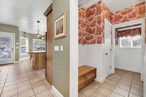 Interior space with light tile patterned floors, a chandelier, and a textured ceiling