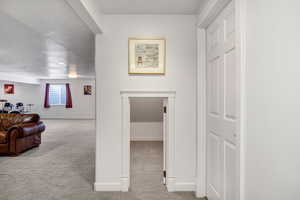 Corridor featuring a textured ceiling and light carpet