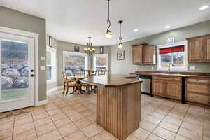 Kitchen with dishwasher, sink, decorative light fixtures, and plenty of natural light