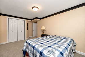 Bedroom with crown molding, a closet, light colored carpet, and a textured ceiling