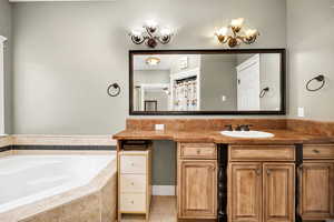 Bathroom with tile patterned floors, a relaxing tiled tub, and vanity