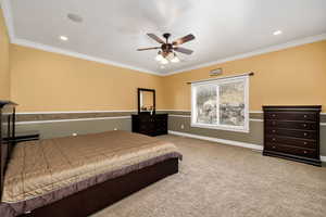 Carpeted bedroom with ceiling fan and ornamental molding