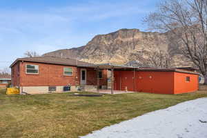 Rear view of property featuring a mountain view, a patio, central AC unit, and a lawn