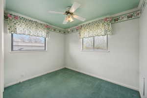 Carpeted spare room featuring plenty of natural light, ceiling fan, and crown molding