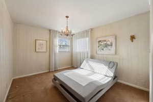 Carpeted bedroom with an inviting chandelier