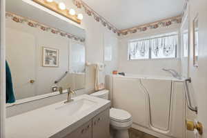 Bathroom featuring hardwood / wood-style flooring, vanity, toilet, and a tub to relax in