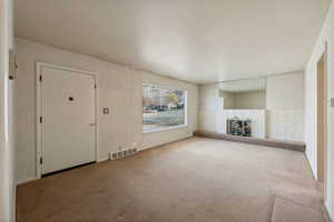 Unfurnished living room with carpet floors and a wood stove