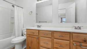 Full bathroom featuring vanity, shower / bath combination with curtain, and toilet