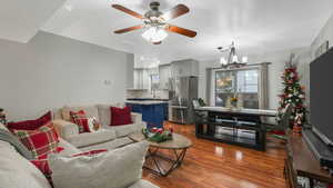 Living room with ceiling fan with notable chandelier, light hardwood / wood-style floors, and sink