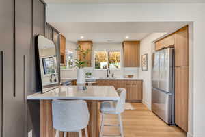 Kitchen with a breakfast bar, stainless steel fridge, light hardwood / wood-style flooring, and sink