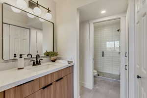 Bathroom featuring tile patterned floors, a shower with door, vanity, and toilet