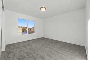 Empty room featuring dark colored carpet