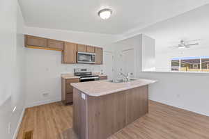 Kitchen with sink, light hardwood / wood-style floors, lofted ceiling, and appliances with stainless steel finishes