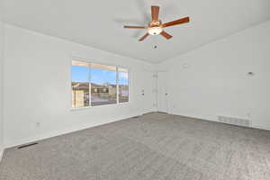 Carpeted empty room featuring ceiling fan and lofted ceiling