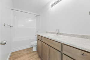 Full bathroom featuring shower / bathing tub combination, hardwood / wood-style floors, vanity, and toilet