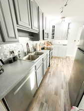 Kitchen featuring sink, appliances with stainless steel finishes, light wood-type flooring, and backsplash