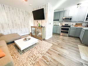 Kitchen with sink, wooden walls, light hardwood / wood-style flooring, decorative backsplash, and appliances with stainless steel finishes