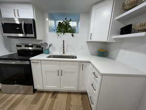 Kitchen featuring sink, white cabinets, stainless steel appliances, and light hardwood / wood-style flooring