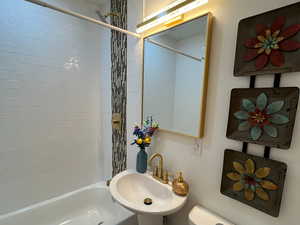 Full bathroom featuring hardwood / wood-style flooring, tiled shower / bath combo, toilet, and sink