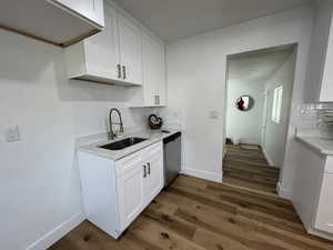 Kitchen with white cabinets, dark hardwood / wood-style flooring, and dishwasher