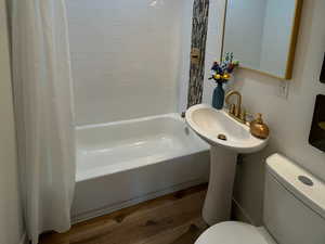 Bathroom featuring toilet, wood-type flooring, and shower / tub combo with curtain