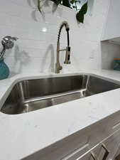 Details featuring backsplash, light stone counters, and sink