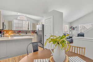 Dining room featuring light hardwood / wood-style floors, sink, and vaulted ceiling