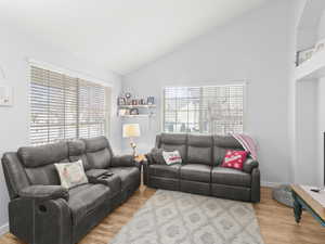 Living room with high vaulted ceiling and light hardwood / wood-style floors