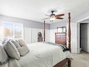 Bedroom featuring a textured ceiling, ceiling fan, and light carpet