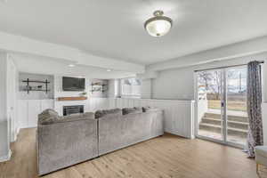 Living room with a fireplace, light hardwood / wood-style flooring, and a healthy amount of sunlight