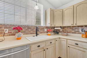 Kitchen featuring pendant lighting, light brown cabinetry, sink, and stainless steel dishwasher