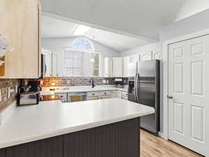 Kitchen featuring sink, tasteful backsplash, kitchen peninsula, light hardwood / wood-style floors, and appliances with stainless steel finishes