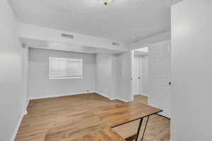 Empty room with light wood-type flooring and a textured ceiling