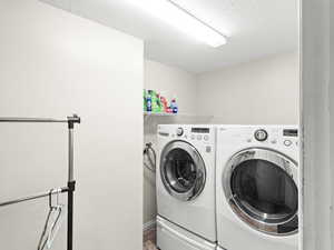 Washroom with separate washer and dryer and a textured ceiling