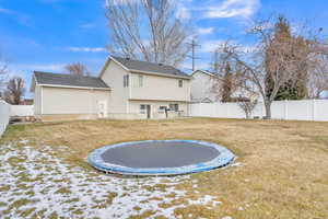 Back of house with a lawn and a trampoline