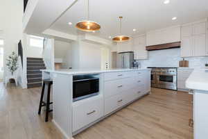 Kitchen with white cabinetry, a kitchen island, light wood-type flooring, and high end appliances