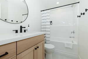 Full bathroom with vanity, toilet, and shower / bath combo with shower curtain